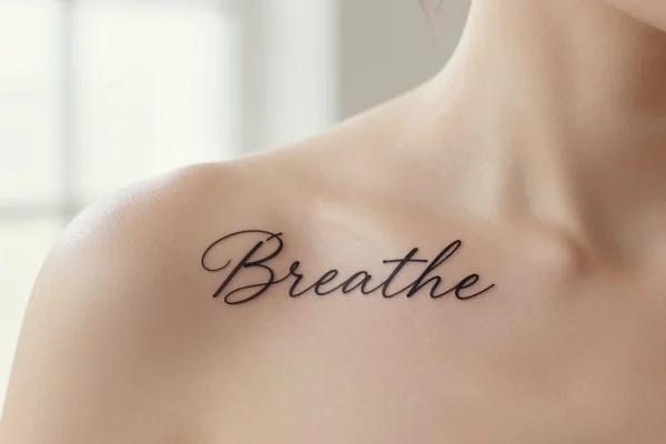 Wrist word tattoo: "Breathe"